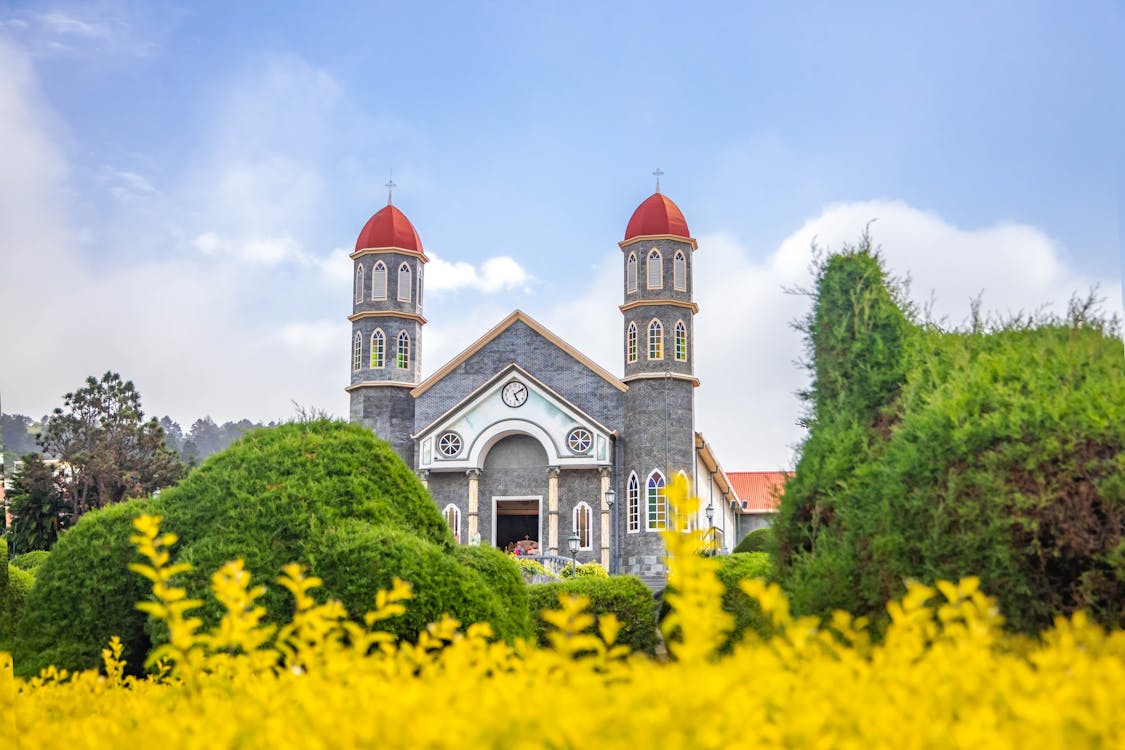 Free Old Catholic church in well maintained garden against blue sky Stock Photo
