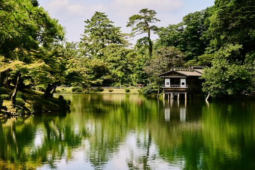 Free Serene summer view of Kenrokuen Garden in Kanazawa, Japan, featuring lush greenery and a peaceful lake. Stock Photo