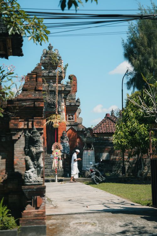 Free A serene view of a traditional Balinese temple with a visitor in white attire. Stock Photo