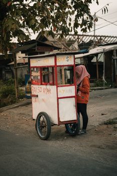 Street vendor with traditional Bakso cart on an urban street, capturing daily life.