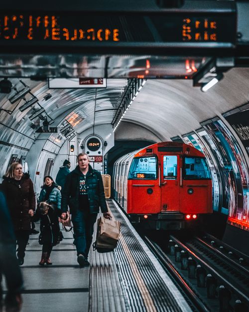 Free Passengers on a bustling London Underground platform as a red train arrives. Stock Photo
