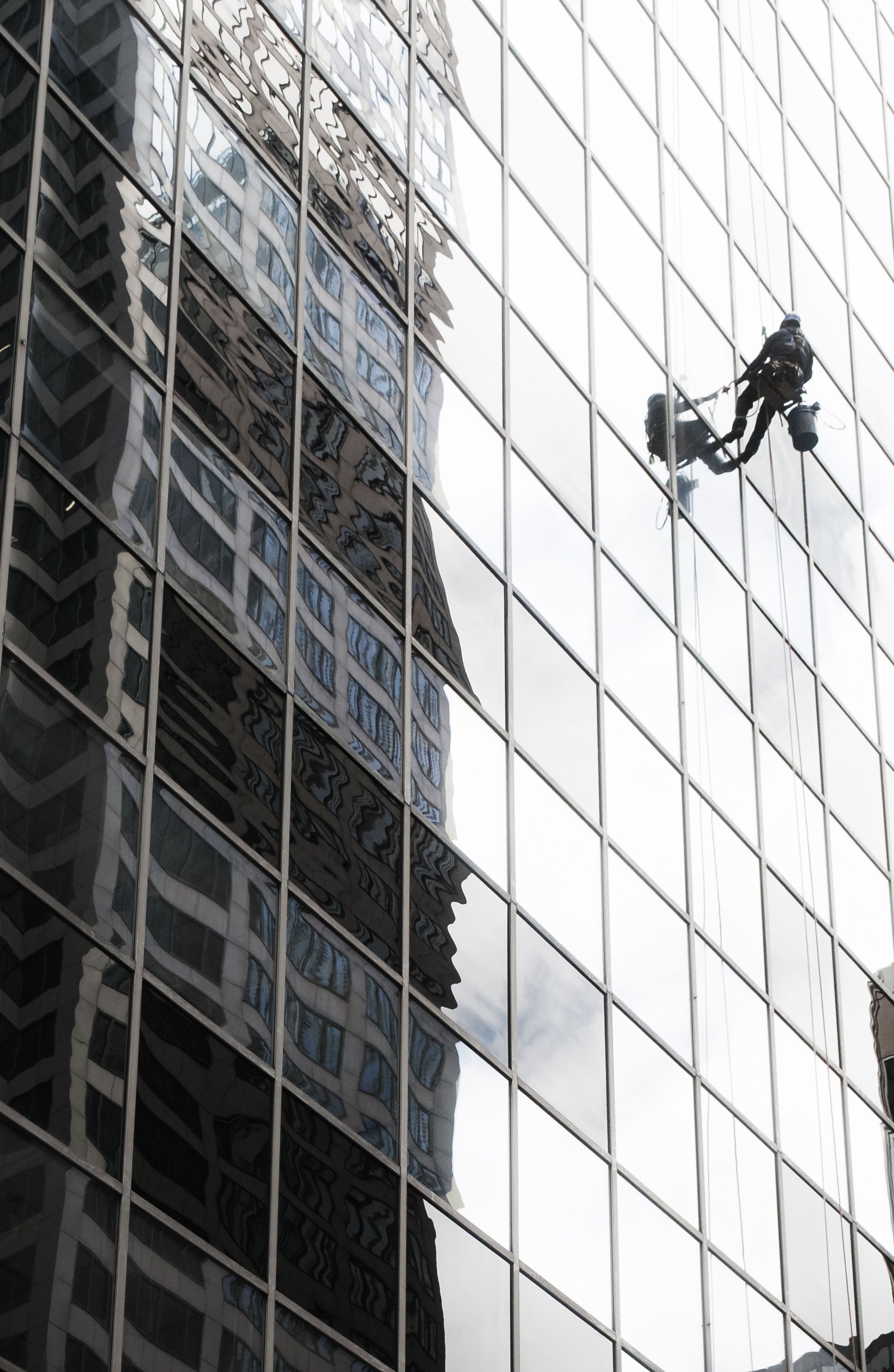 A window cleaner works on a high-rise building facade in Chicago, reflecting the cityscape.