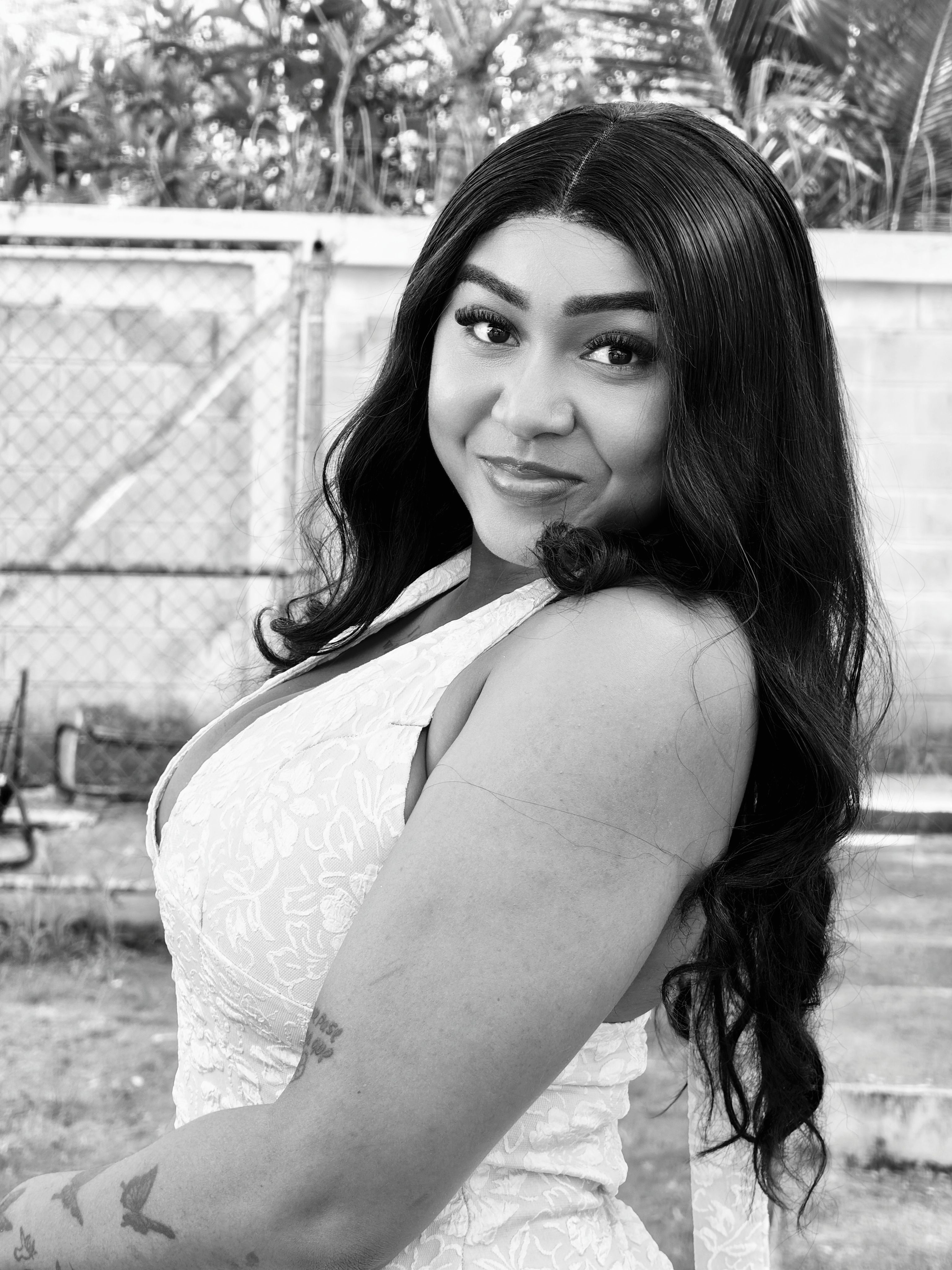 Charming black and white portrait of a smiling woman with long hair, posing outdoors with a confident expression.