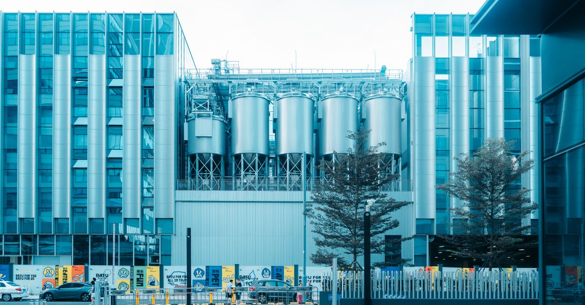 Contemporary industrial building with steel silos and urban surroundings in daylight.
