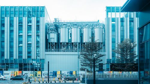 Free Contemporary industrial building with steel silos and urban surroundings in daylight. Stock Photo