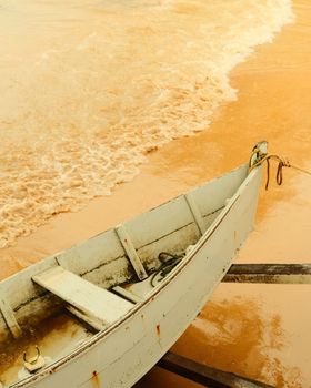 A weathered boat rests on the sandy shores of Espírito Santo, Brazil with gentle waves in the background.