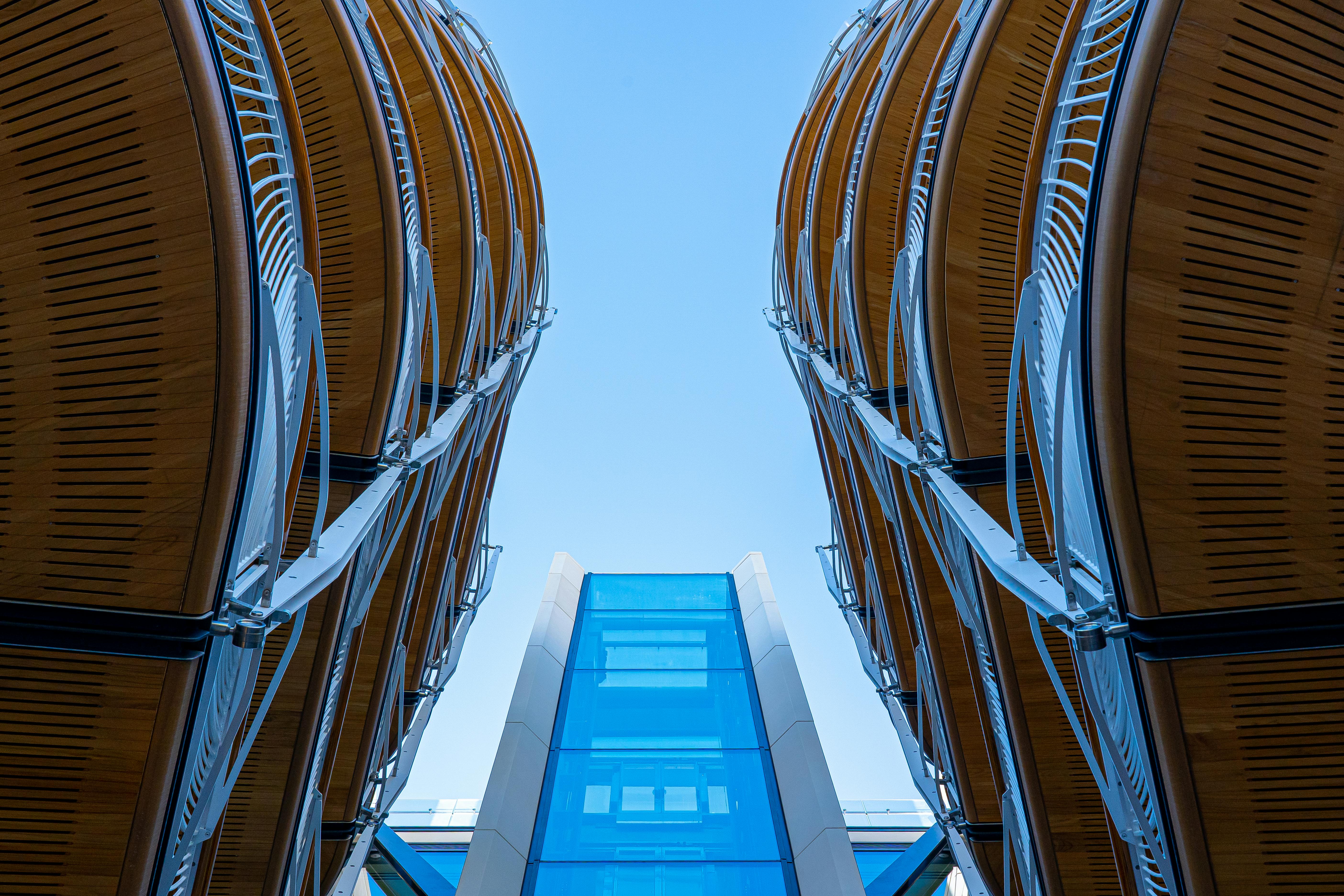 采用低角度拍摄的现代建筑设计，以弯曲的钢和玻璃元素为特色，突出了对称性与创新性