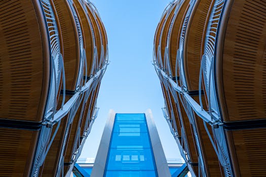 采用低角度拍摄的现代建筑设计，以弯曲的钢和玻璃元素为特色，突出了对称性与创新性