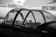 A detailed monochrome view of a vintage airplane cockpit with a focus on the canopy and rivets.