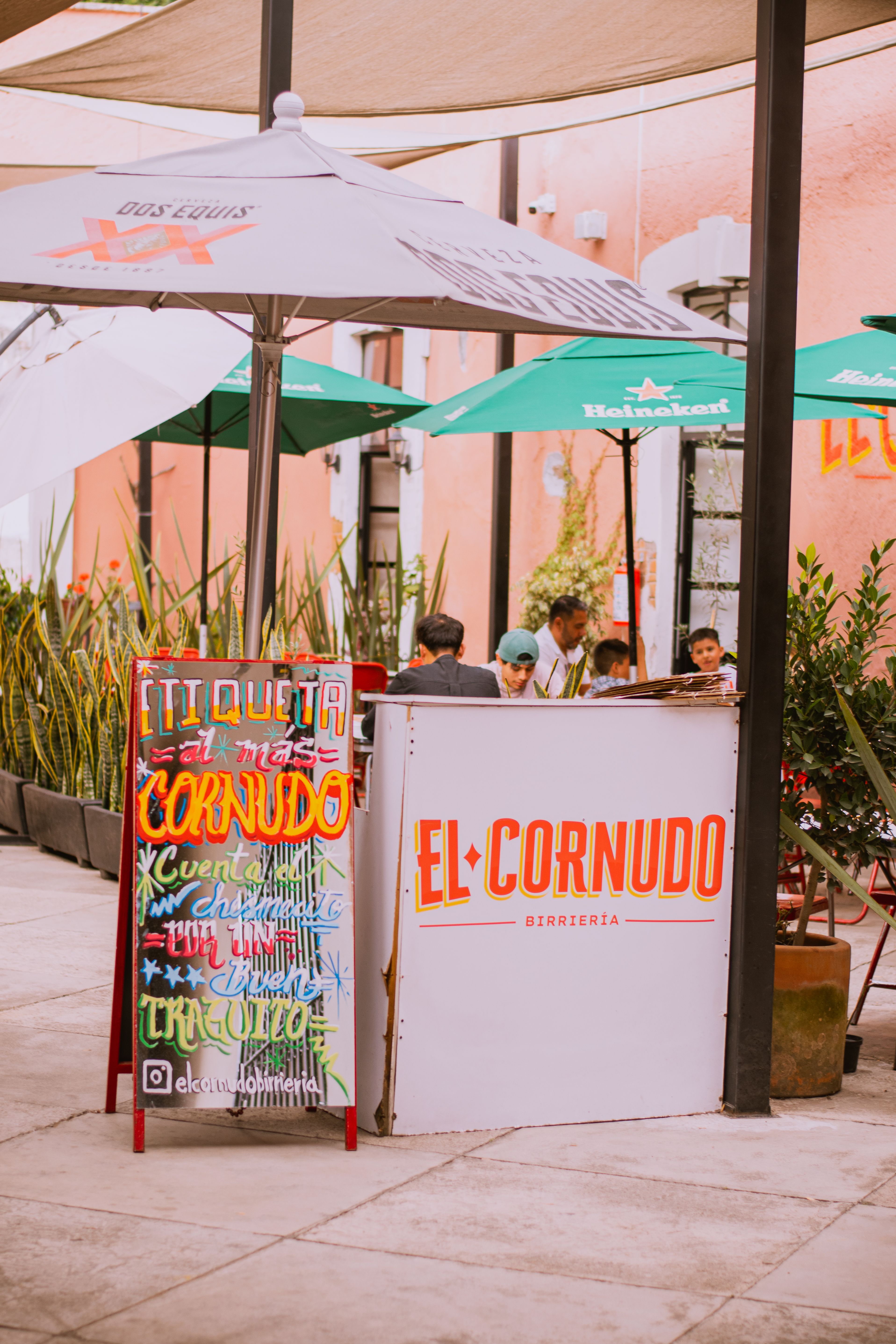 Colorful outdoor patio of El Cornudo restaurant with vibrant decor and people dining.