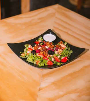 Vibrant berry salad with mixed greens and fresh dressing on a modern plate.
