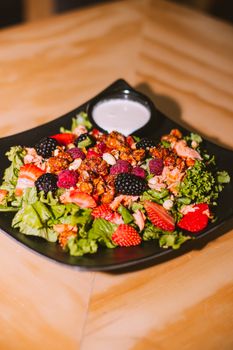 A colorful berry and nut salad with fresh greens and dressing, perfect for a healthy meal.