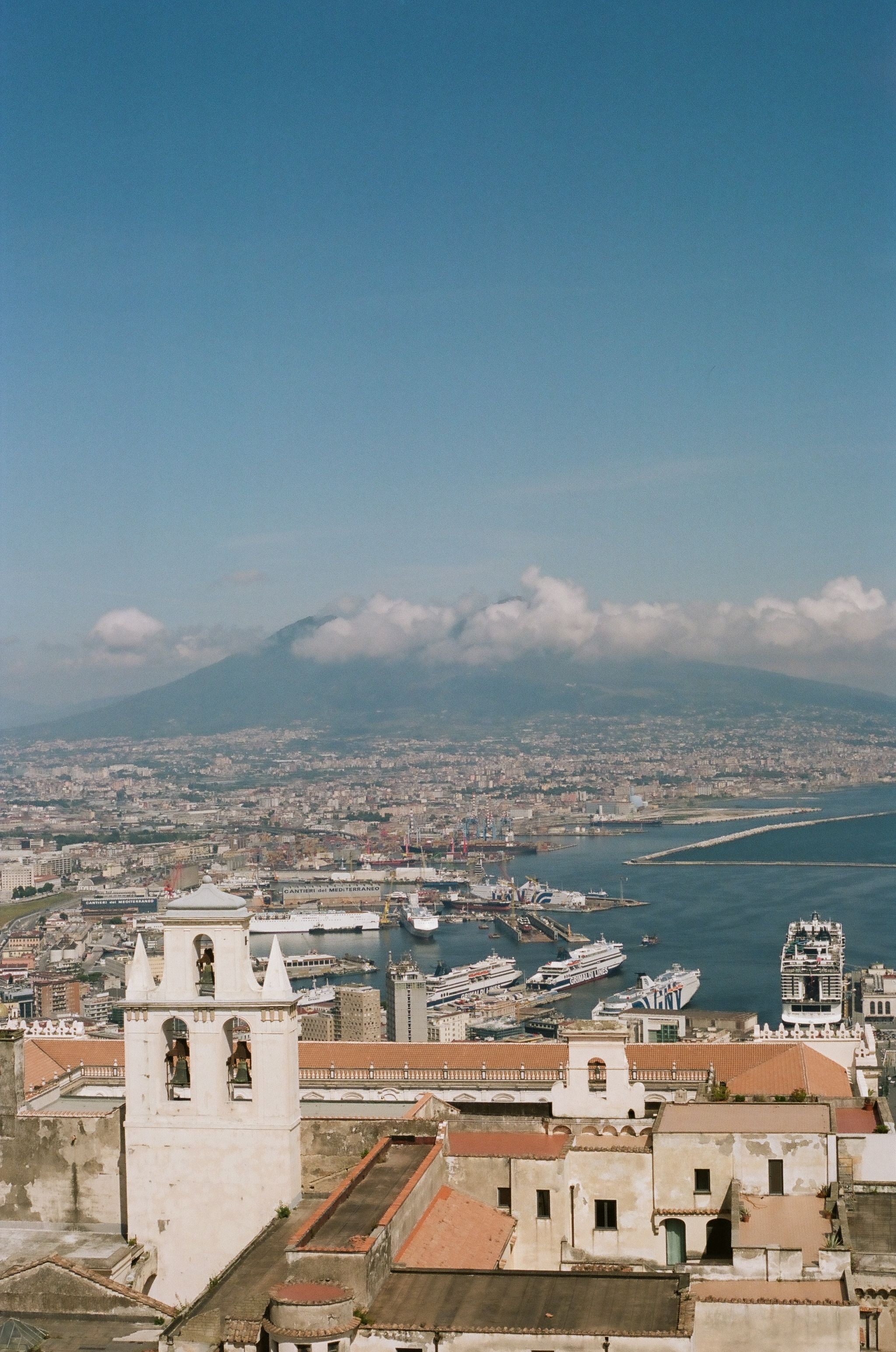 Aerial view of Naples, Italy, featuring Mount Vesuvius and the coast.