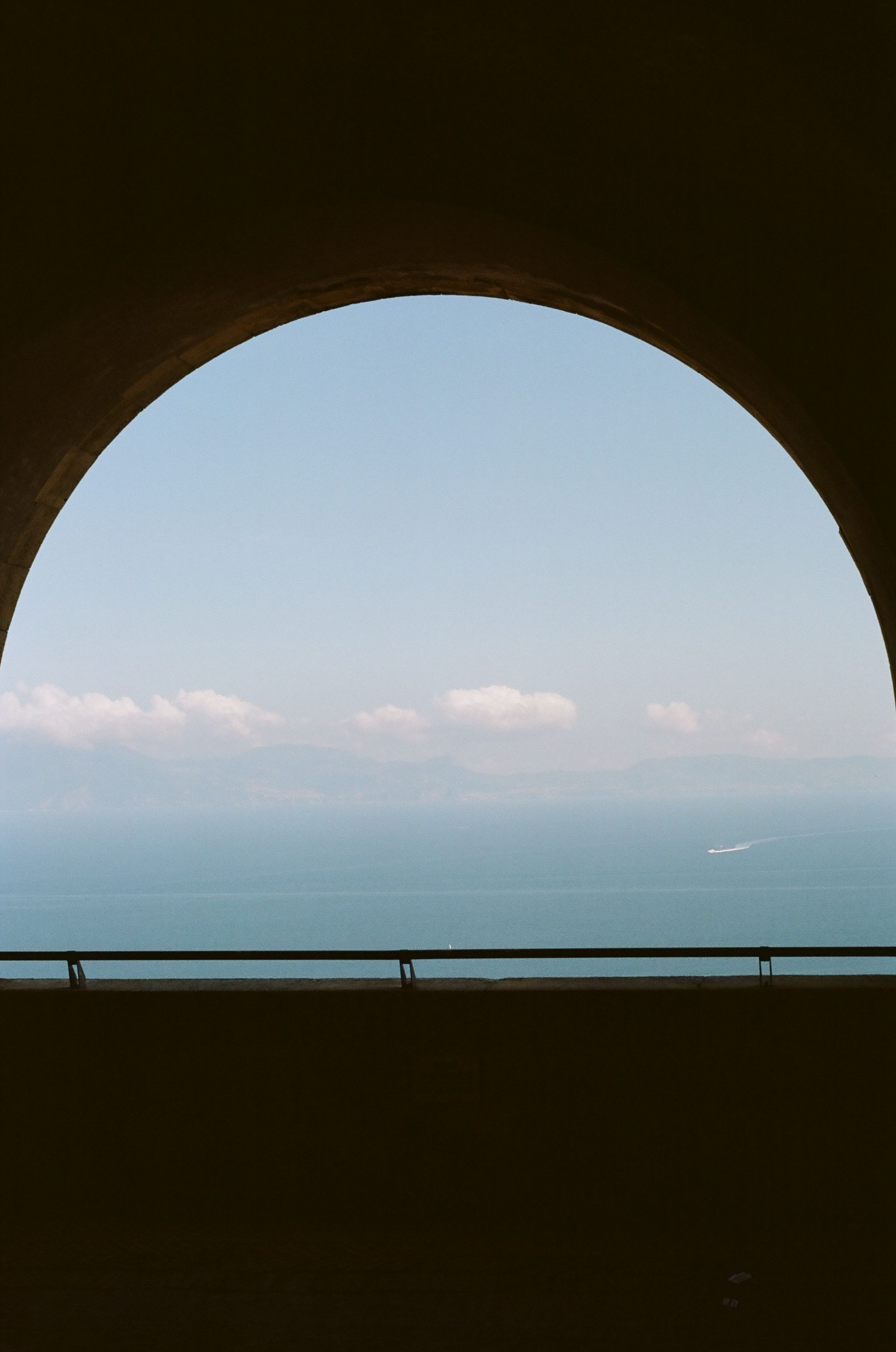 Stunning view of the Mediterranean Sea framed by an arched structure in Naples, Italy, conveying tranquility.