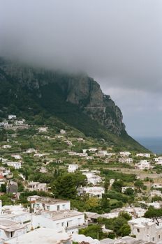 Breathtaking view of Capri's lush landscape and coastal cliffs under dramatic clouds.