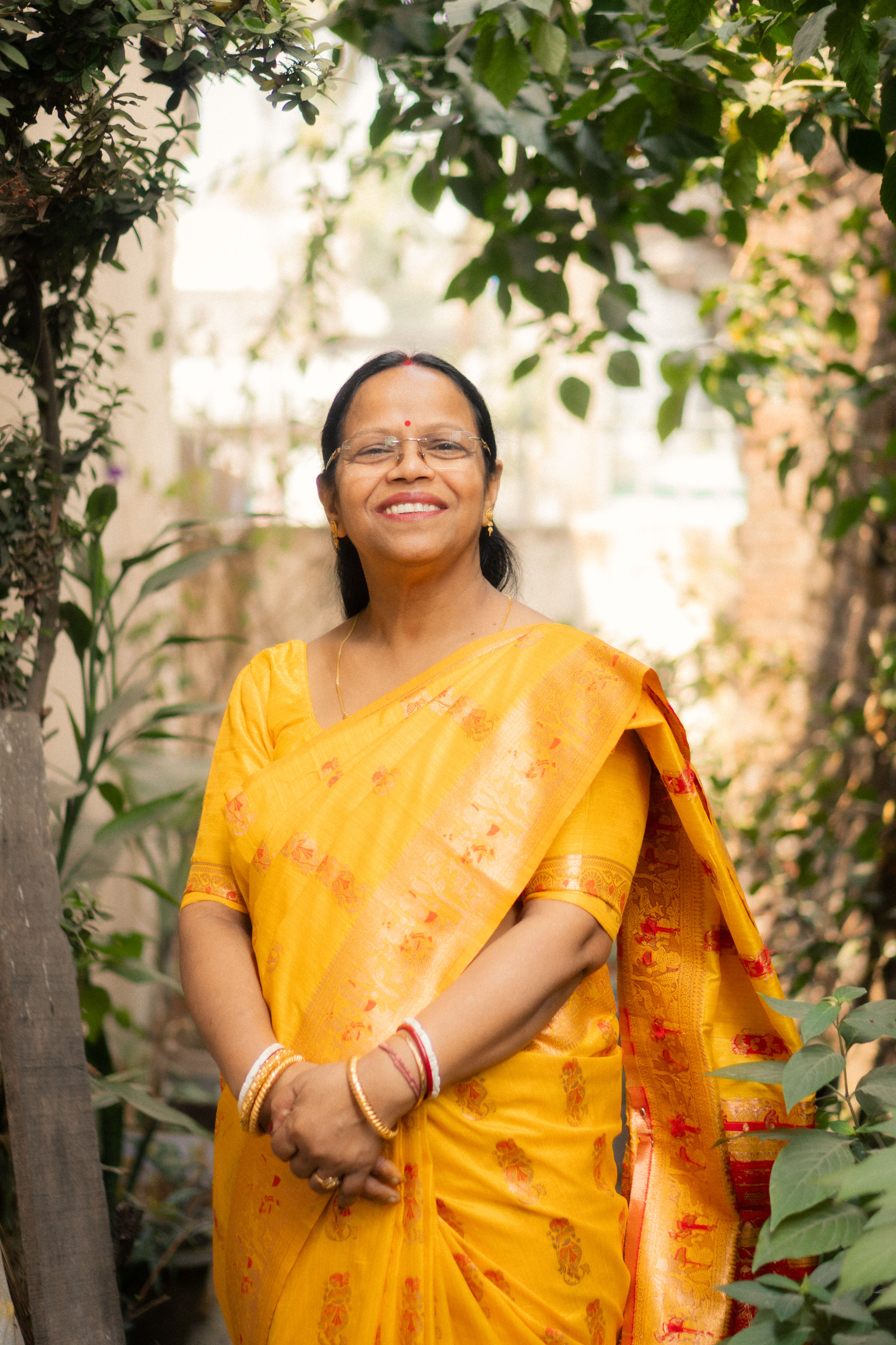 A happy woman in a yellow sari enjoying a sunny day outdoors.