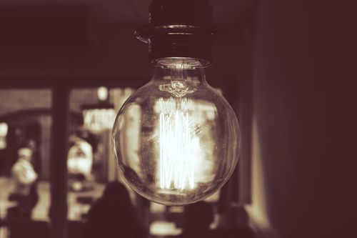 Free A sepia-toned close-up of a glowing vintage light bulb indoors. Stock Photo