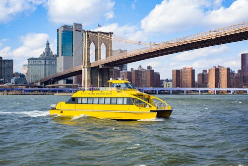 Yellow vessel boat sailing on river near bridge