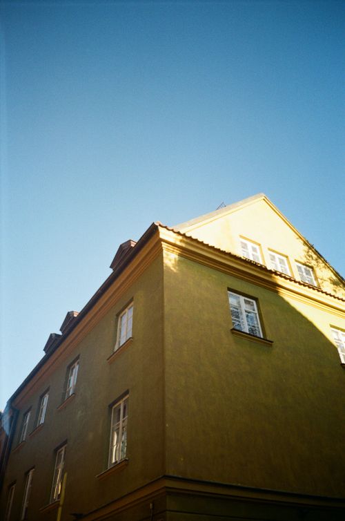 Free Corner view of a historic yellow building in Warsaw, showcasing European architectural style under a clear blue sky. Stock Photo
