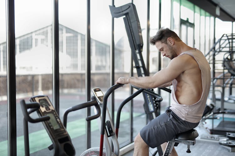 Strong Sportsman Using Exercise Bike In Gym