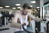 精疲力竭的男性运动员在现代体育中心，一边在运动机上进行肌肉训练，一边进行耐力训练