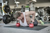 Muscular sportsman doing push ups on kettlebells in gym