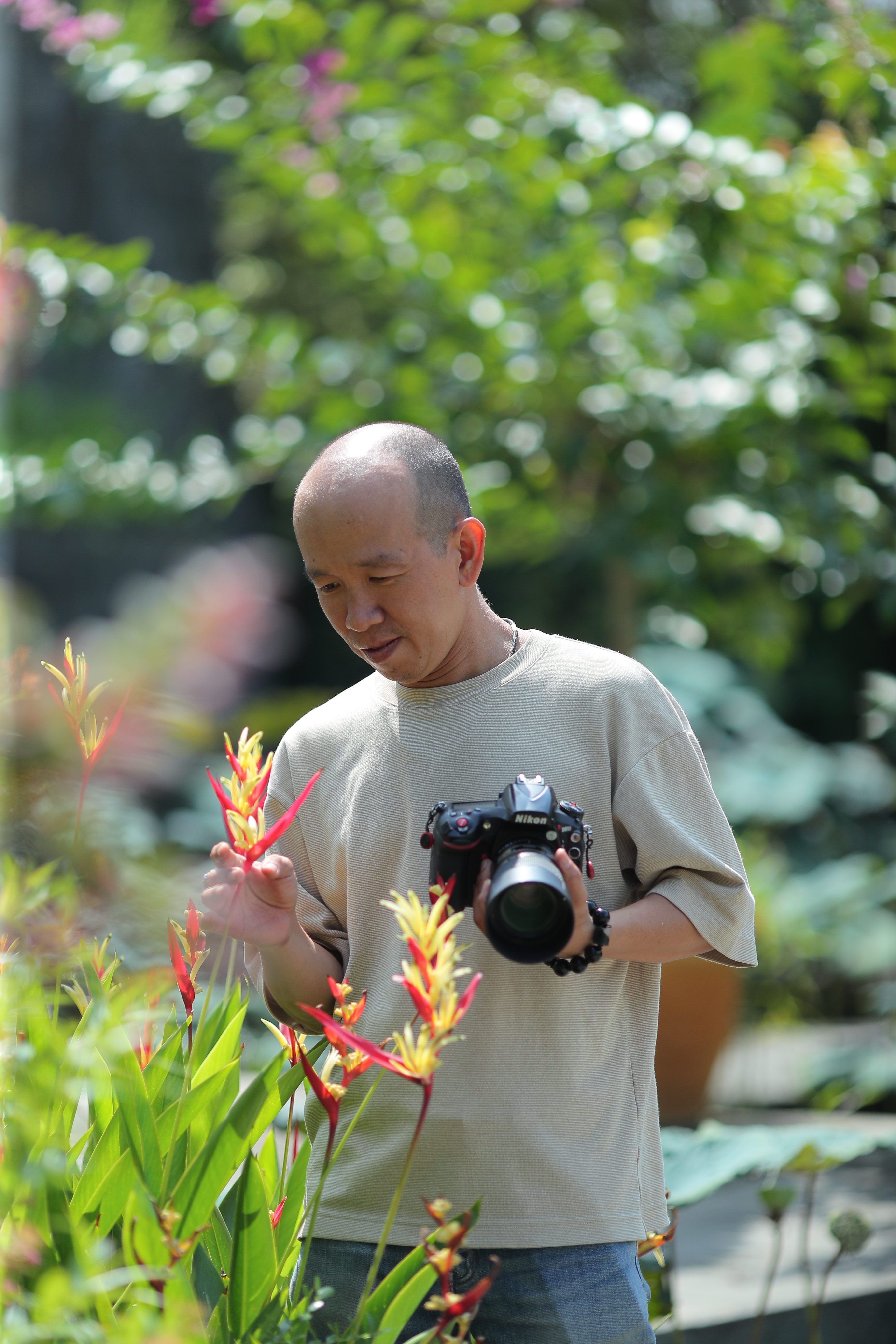 Photographer capturing vibrant tropical flowers in a lush garden setting.