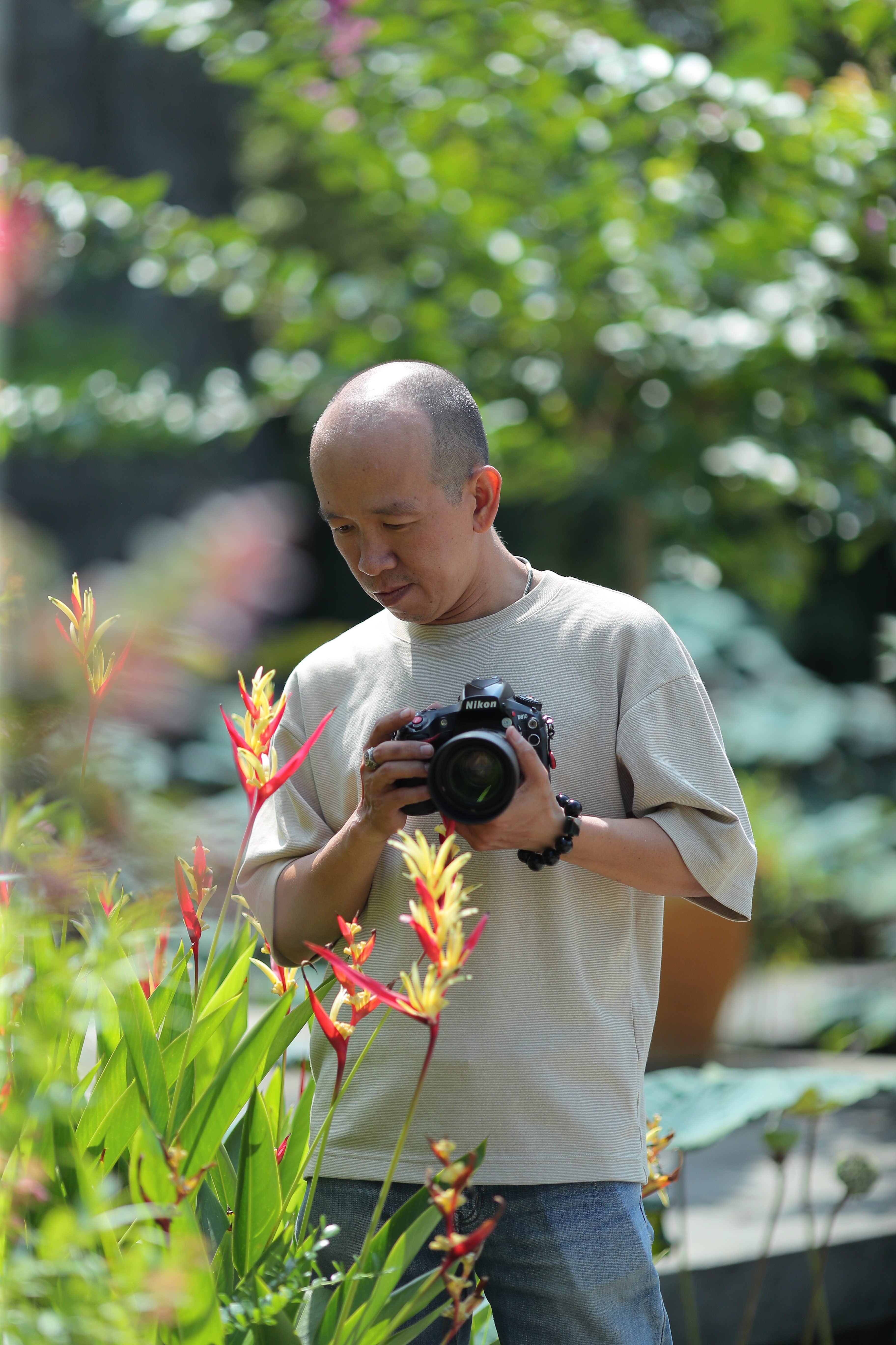 Man photographing vibrant flowers in a sunny garden.