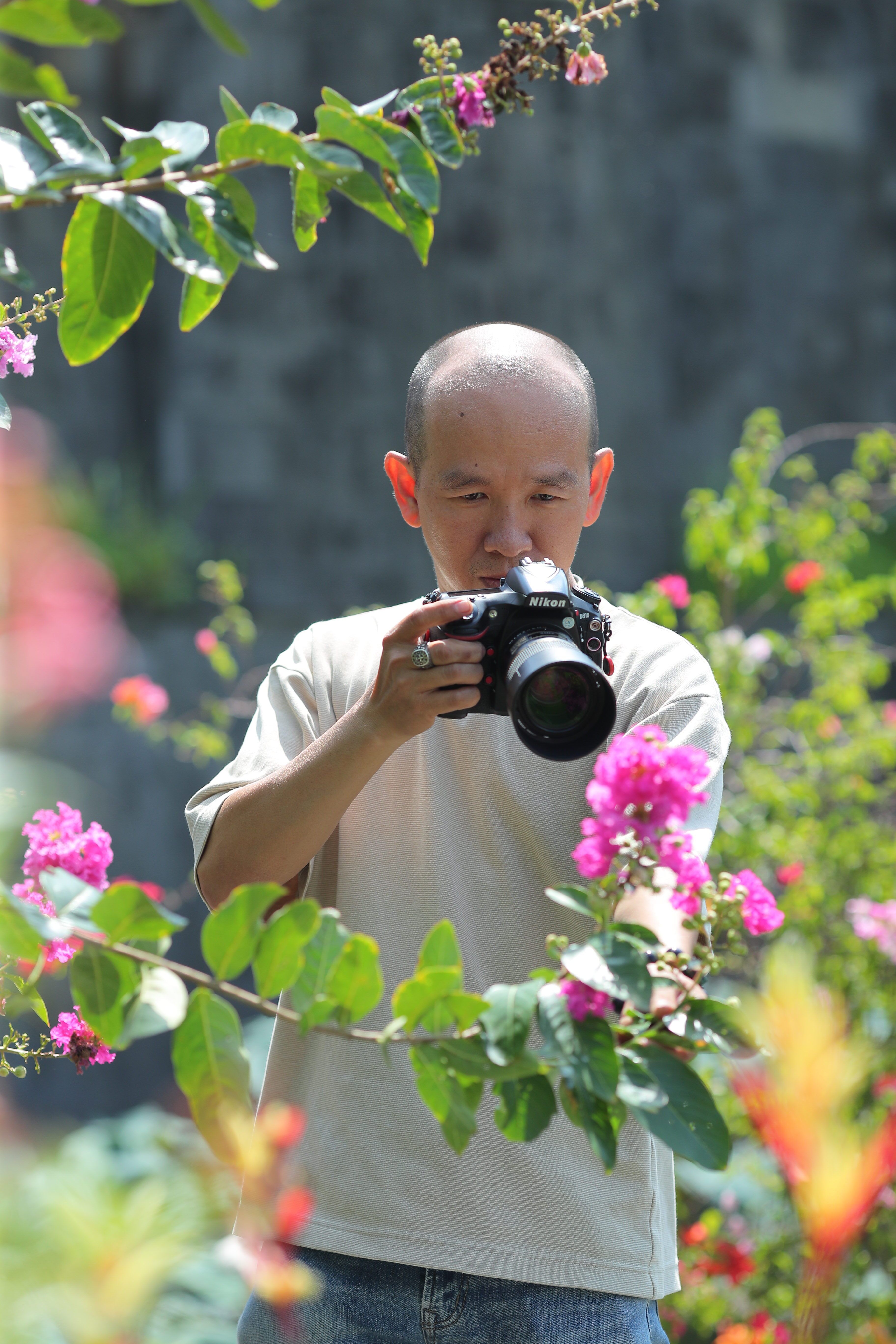 Man photographing vibrant flowers in a lush garden setting.