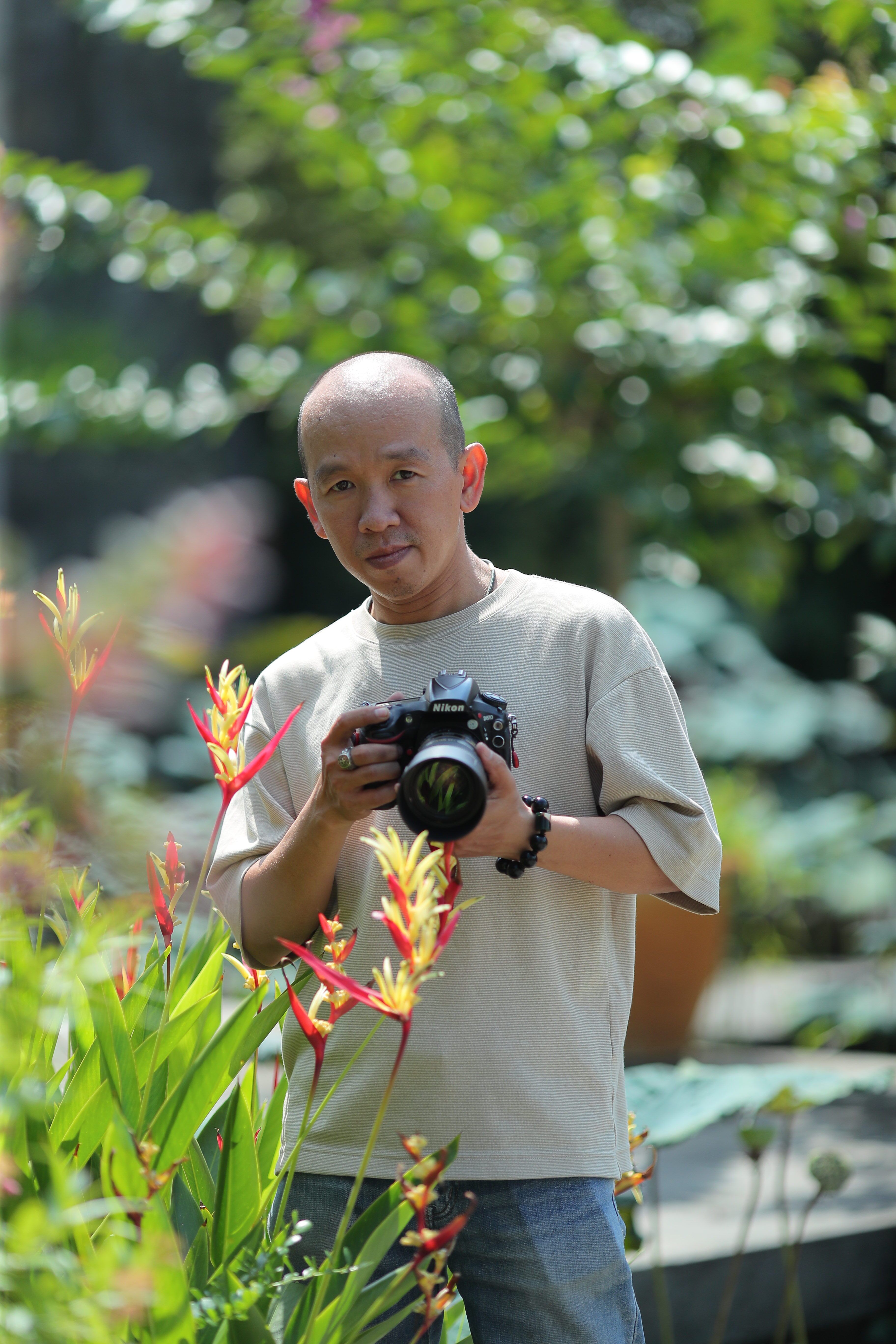 Man with camera surrounded by vibrant garden foliage.