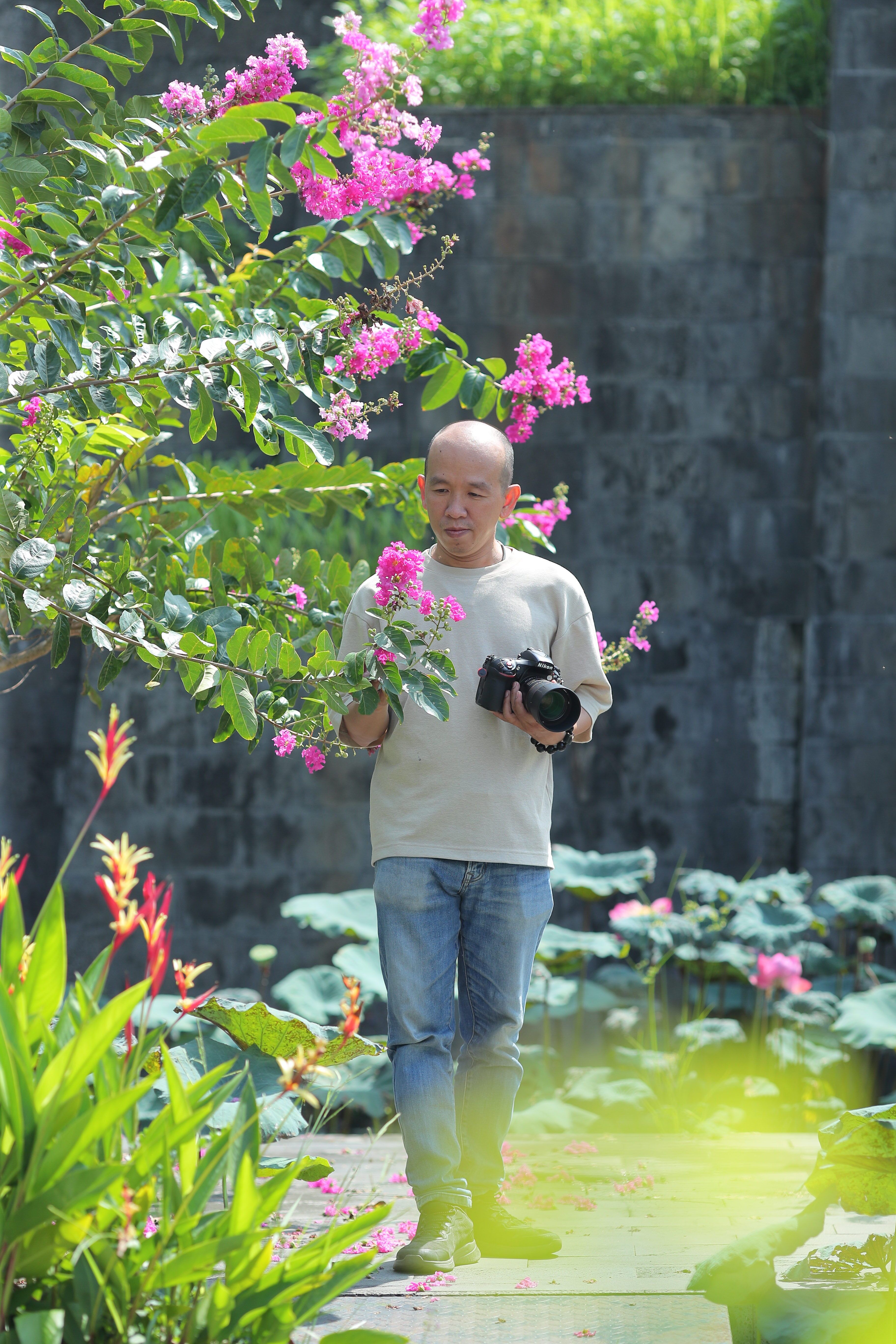 Man photographing vibrant flowers in serene garden setting.
