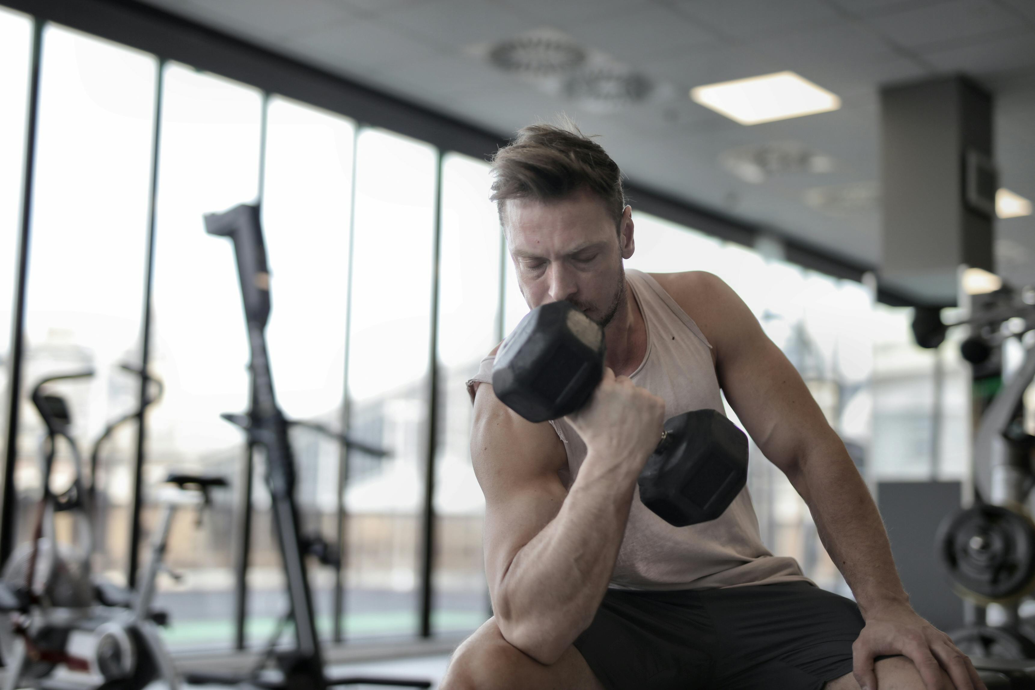 Determined muscular sportsman exercising with dumbbell · Free Stock Photo