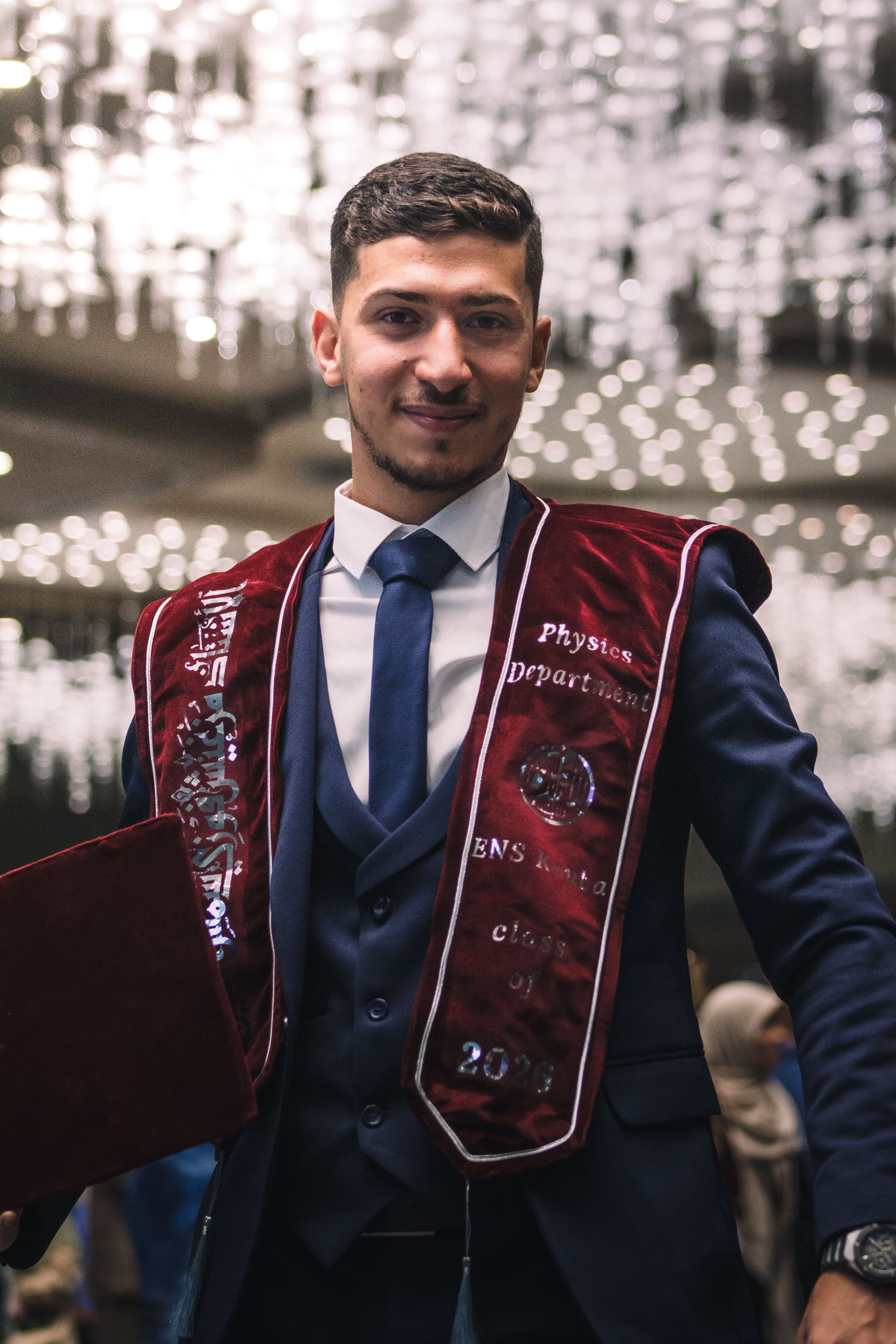 A young graduate in formal attire celebrating graduation in Staoueli, Algeria.