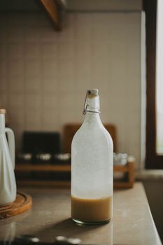 Minimalist scene of a ceramic bottle on a rustic kitchen counter with soft lighting.