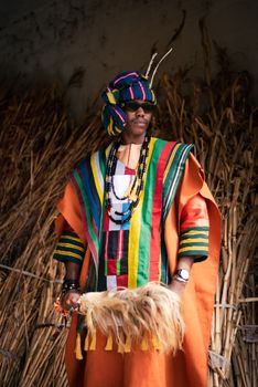 A man in vibrant traditional Nigerian attire poses outdoors in Jos.