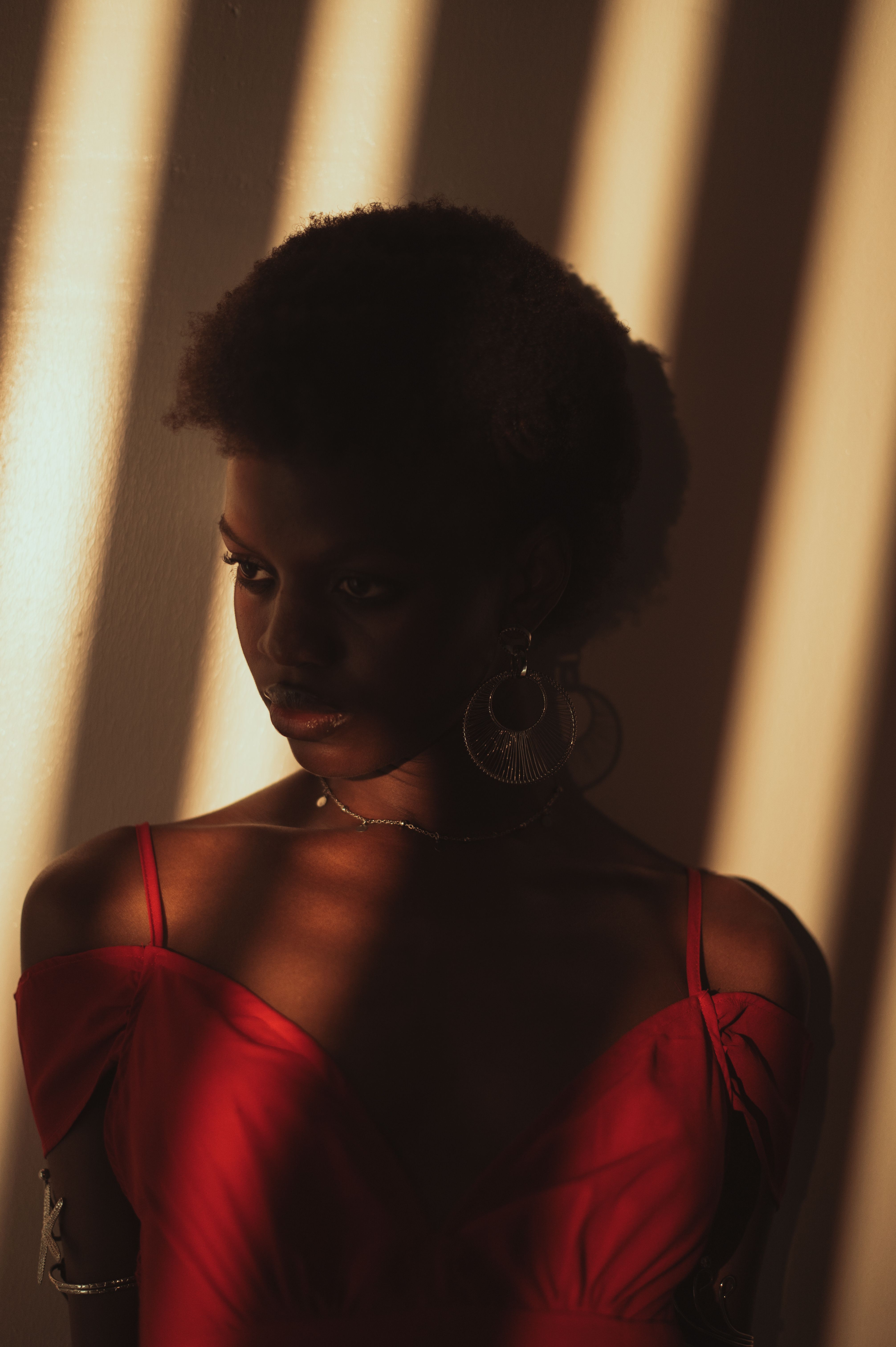 Portrait of a woman in red dress with artistic sunlight shadows in Abuja.