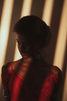 Portrait of a woman in red dress with artistic sunlight shadows in Abuja.