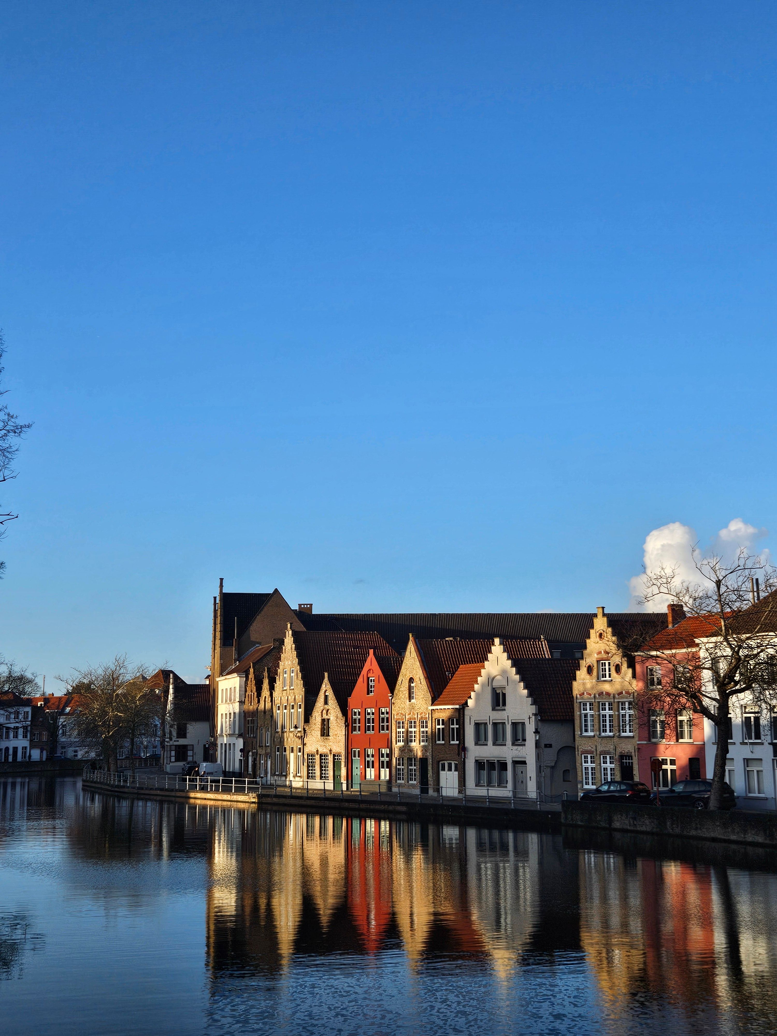 Picturesque view of colorful buildings reflecting on a canal in Bruges, Belgium.