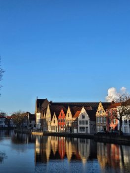 Picturesque view of colorful buildings reflecting on a canal in Bruges, Belgium.