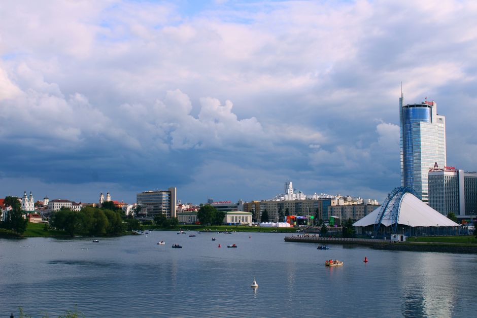 Picturesque view of Minsk cityscape along the river under a cloudy sky with modern and historic architecture.