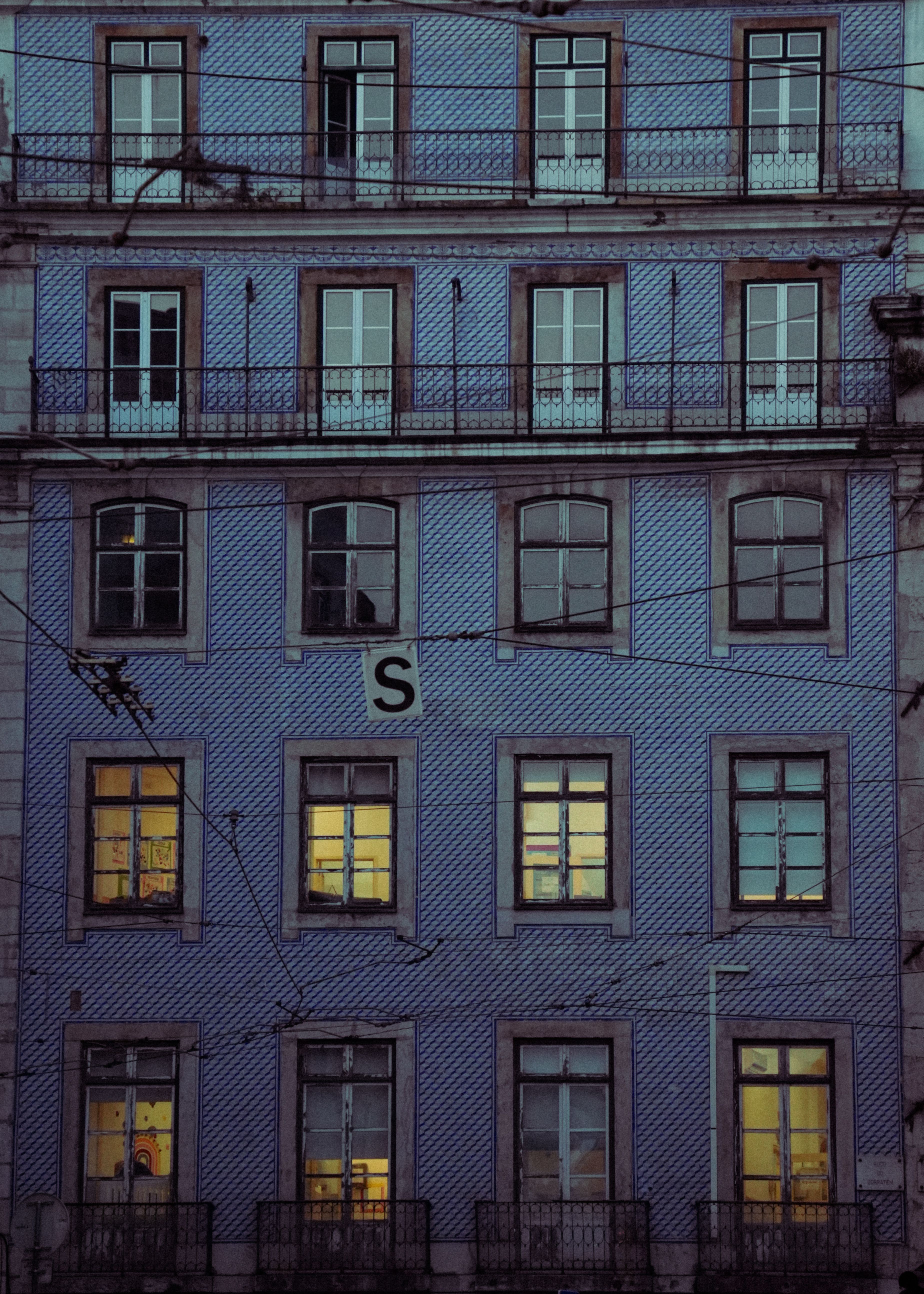 A classic blue building facade with illuminated windows at twilight, featuring intricate design.