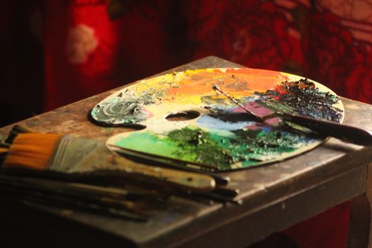 Colorful artist's palette with brushes on a table, bathed in warm light.. pexels, colorful, artists