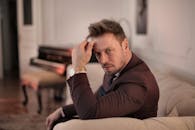 一位衣冠楚楚的男子坐在优雅的客厅里，散发着自信与格调