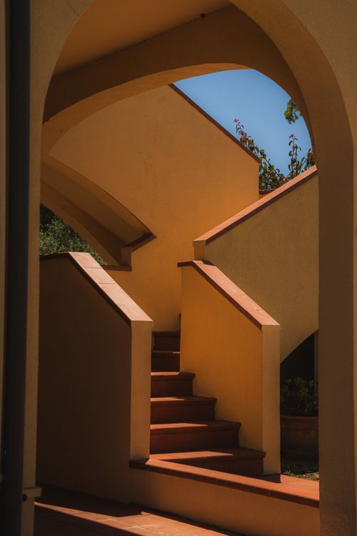 Free An elegant architectural staircase with terracotta steps framed by arches in soft sunlight. Stock Photo