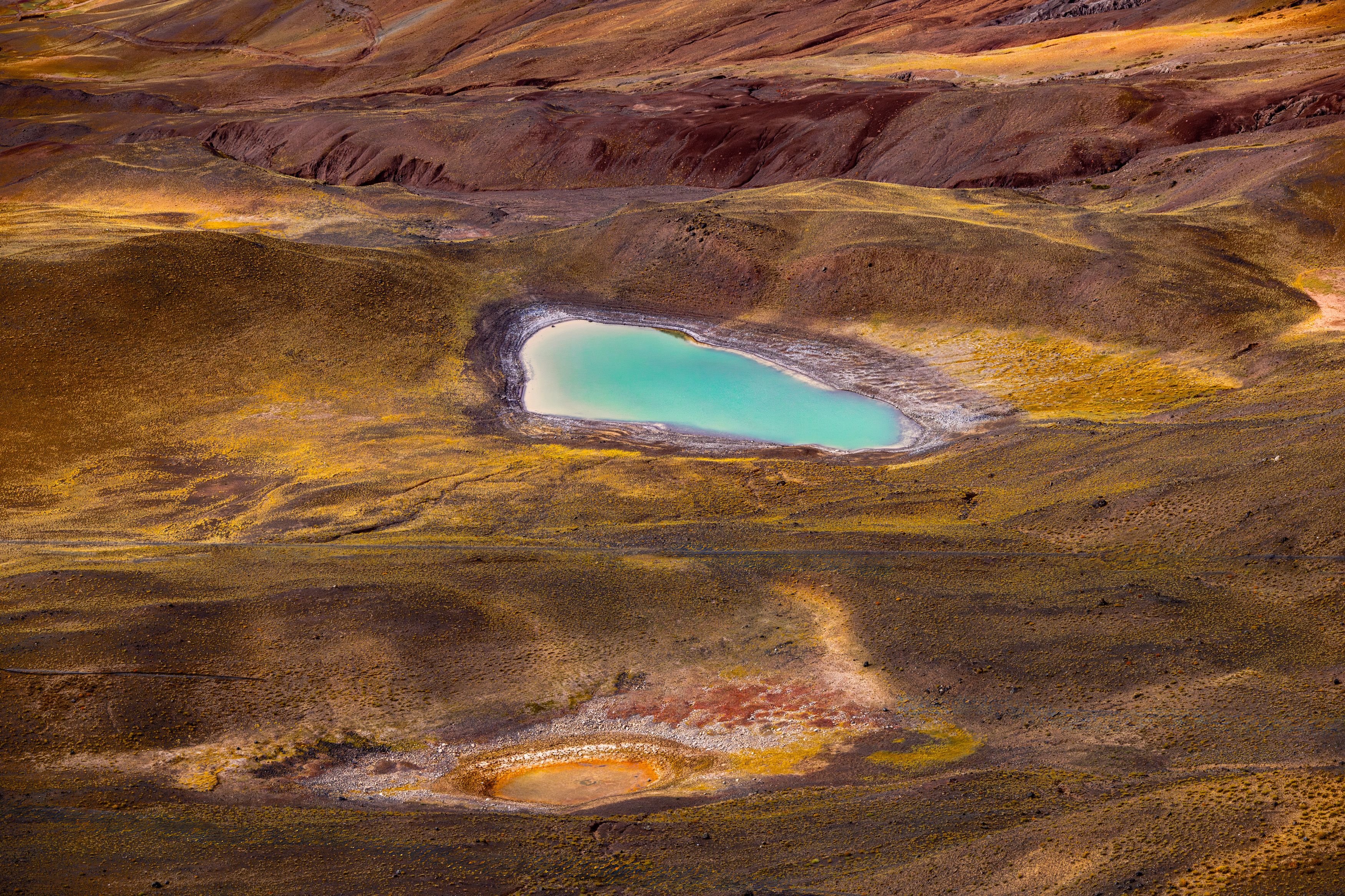 Stunning aerial view of a vibrant turquoise lake in a barren landscape, highlighting natural beauty.