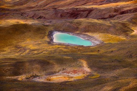 Stunning aerial view of a vibrant turquoise lake in a barren landscape, highlighting natural beauty.