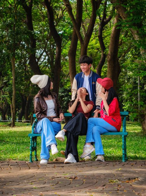 Free A joyful group of friends sharing a laugh on a park bench in Jakarta, Indonesia. Stock Photo