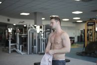 Sweaty shirtless sportsman resting after training in gym