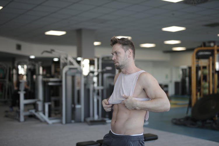 Strong Athletic Man Putting On Sportswear In Gym