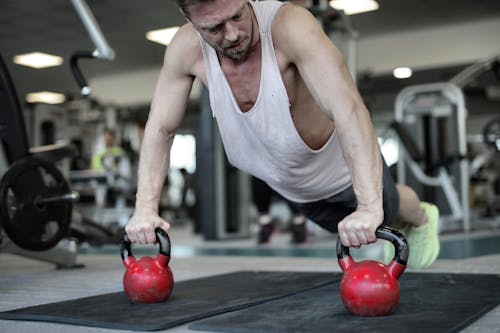 Muscular sportsman pushing up on kettlebells